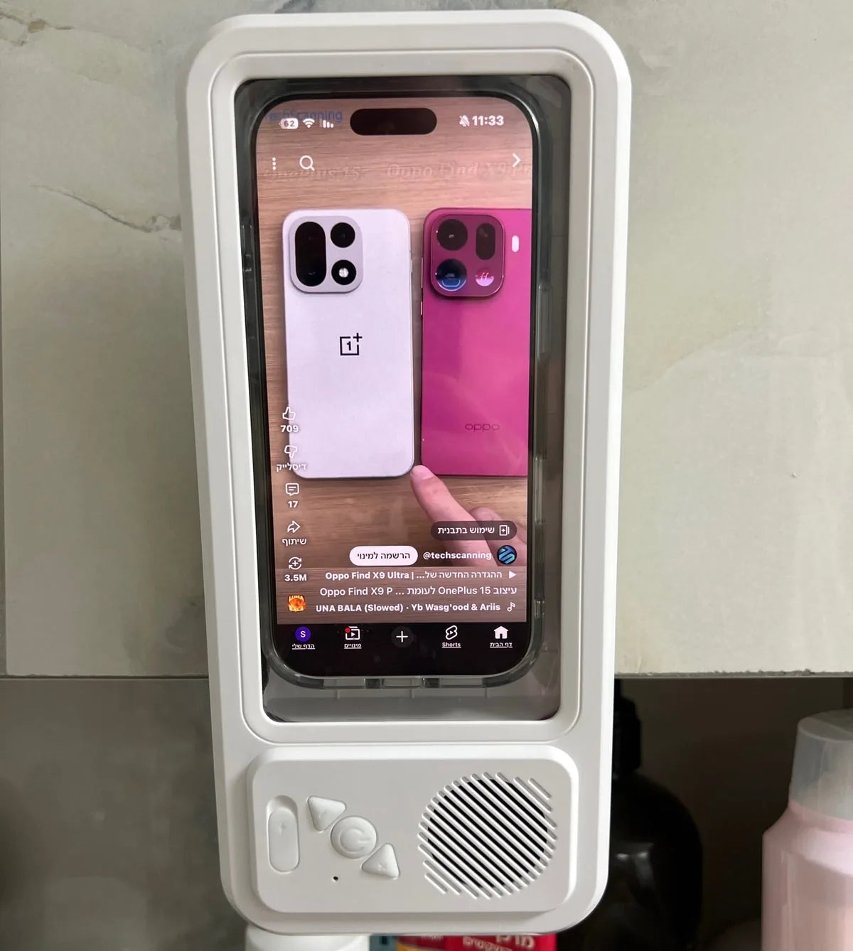 Real white phone holder with screen and speaker mounted on a tiled bathroom wall